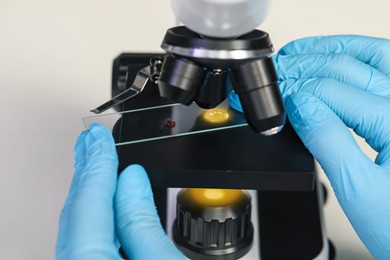 Scientist examining sample on slide under microscope, closeup