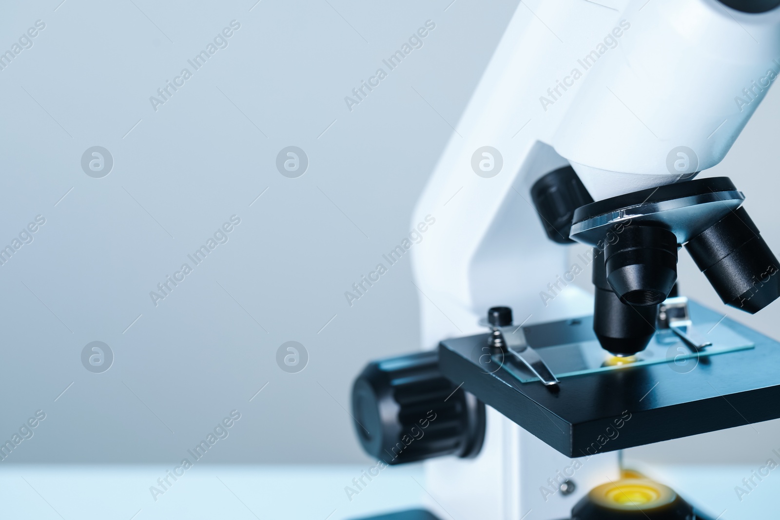 Photo of Science. Microscope with glass slide on blurred background, closeup. Space for text