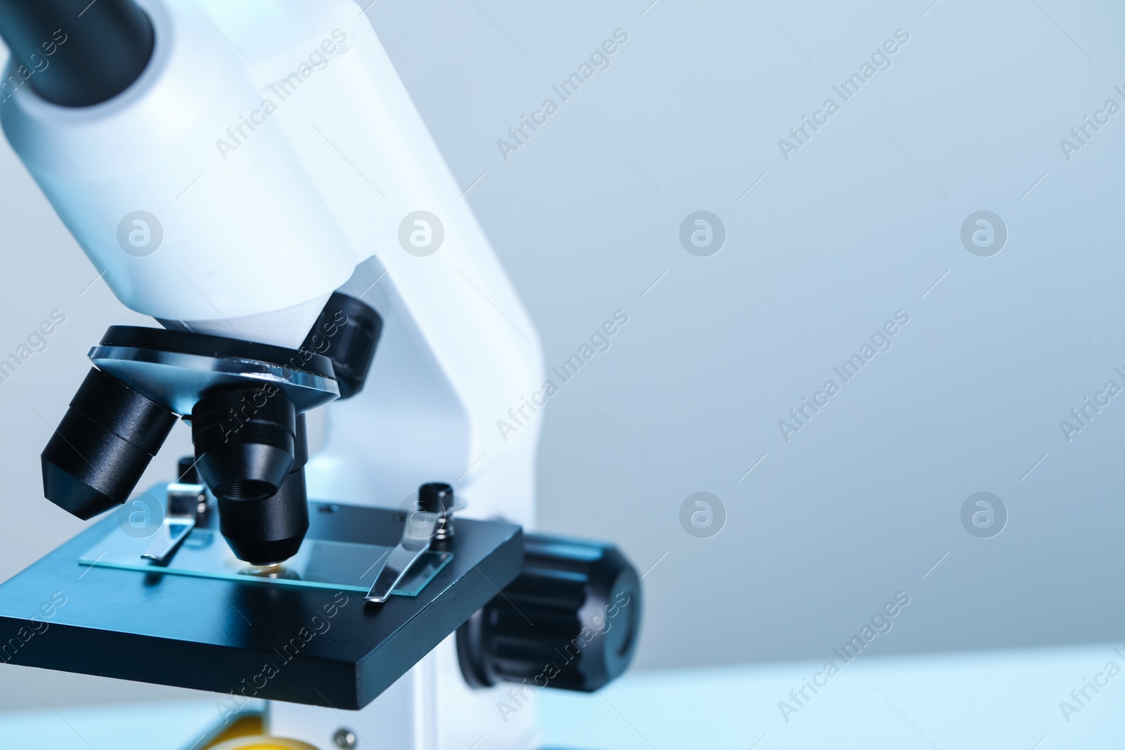 Photo of Science. Microscope with glass slide on blurred background, closeup. Space for text