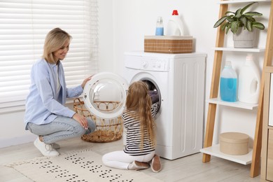 Little girl helping her mom doing laundry at home