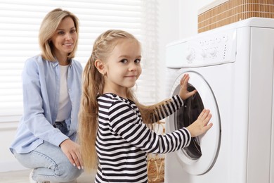 Little girl helping her mom doing laundry at home