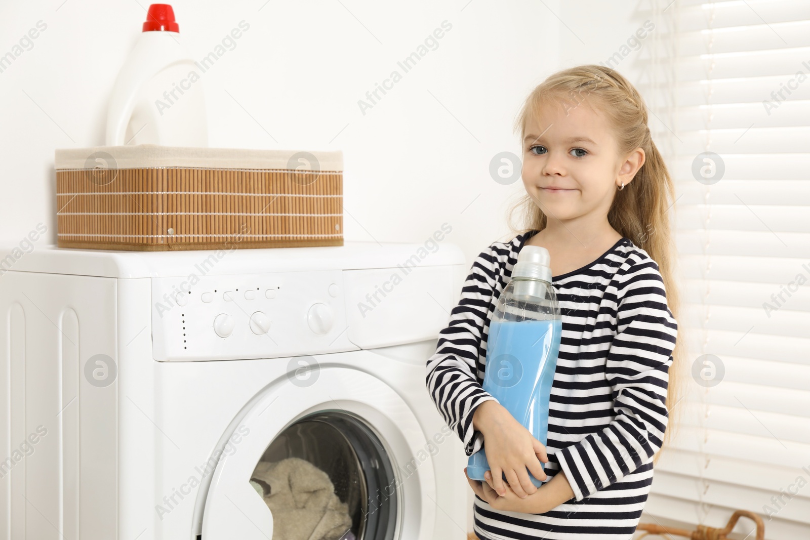 Photo of Little helper. Cute girl doing laundry at home