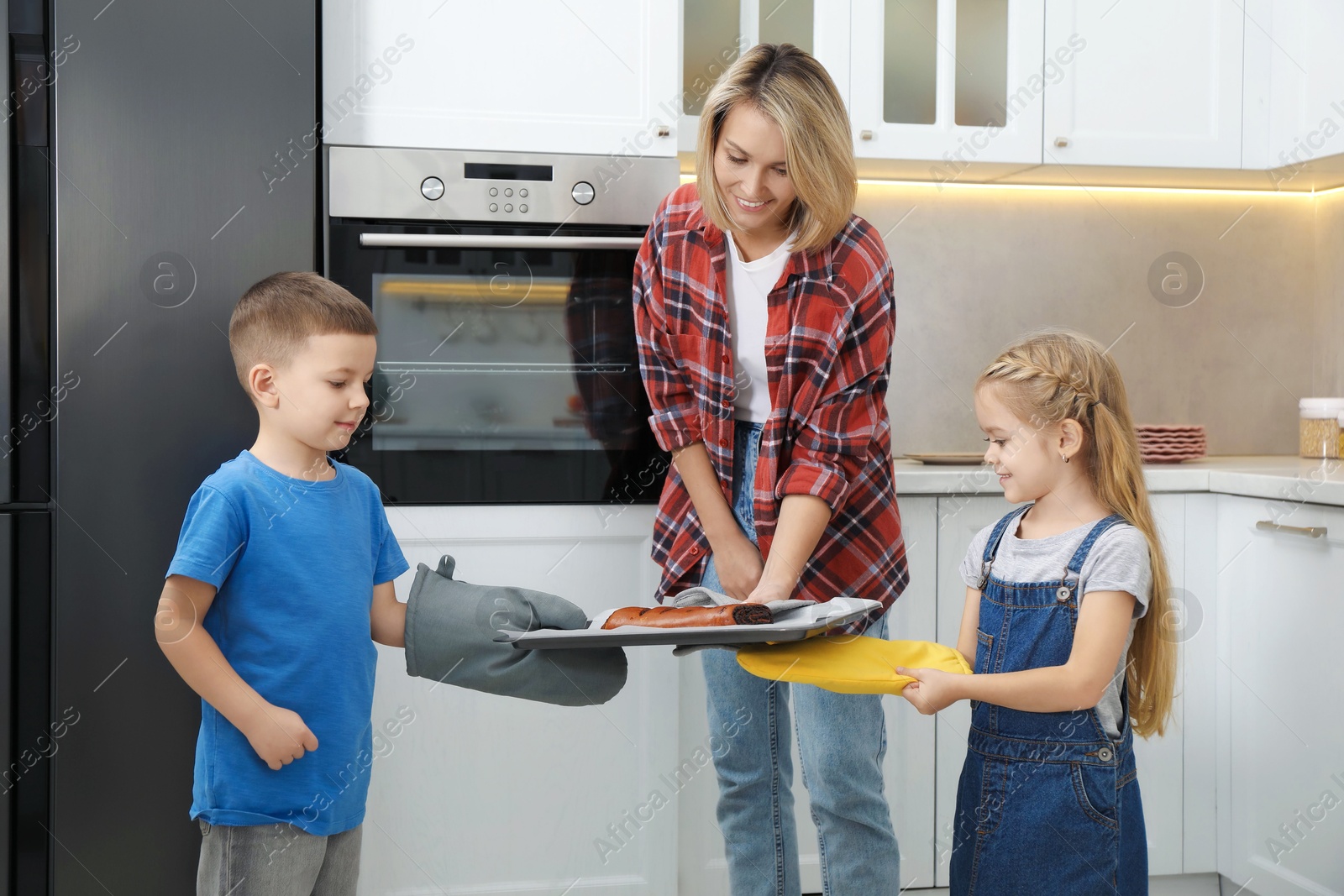 Photo of Little helpers. Children baking with their mother at home