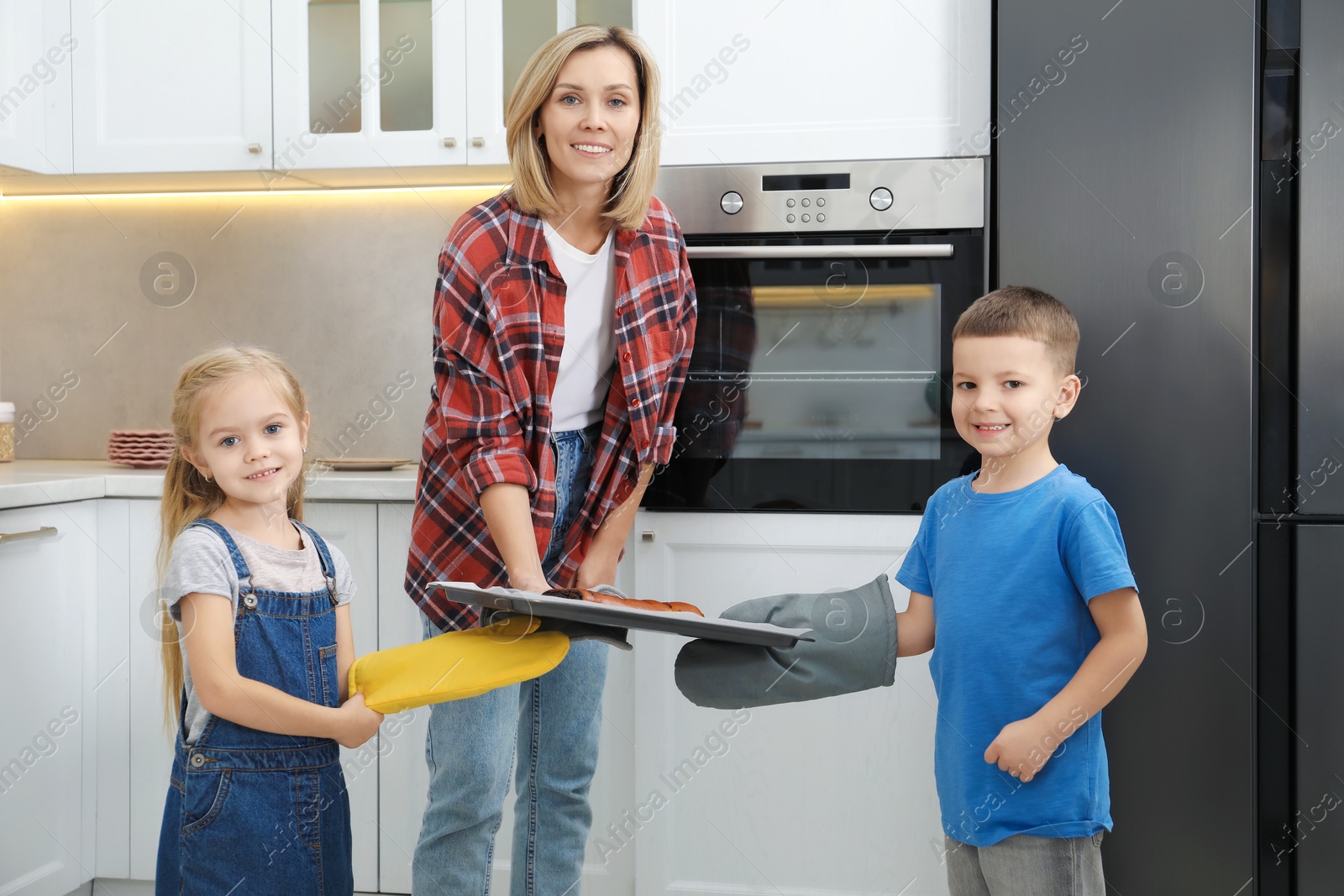 Photo of Little helpers. Children baking with their mother at home