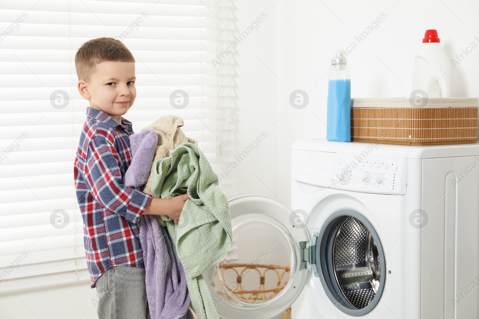 Photo of Little helper. Cute boy doing laundry at home