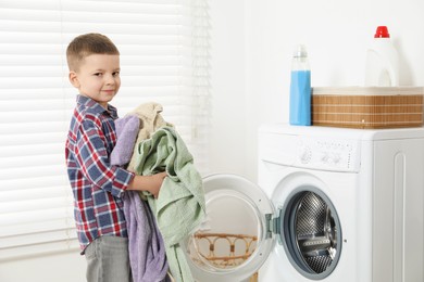 Photo of Little helper. Cute boy doing laundry at home