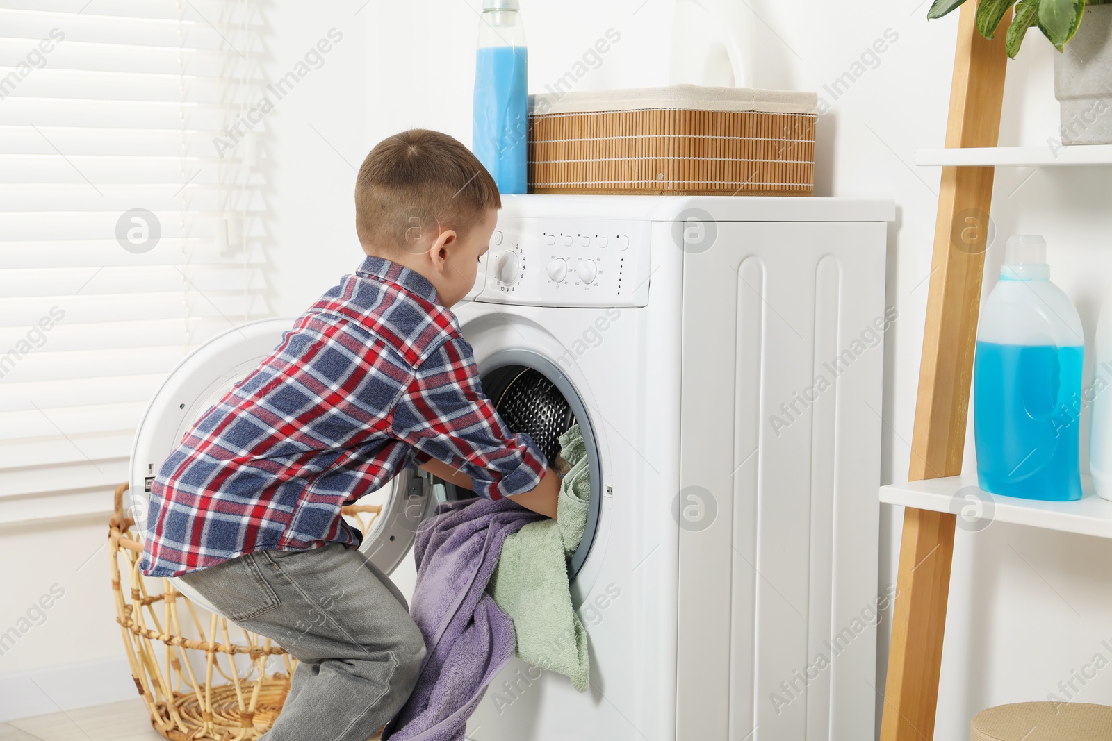 Photo of Little helper. Cute boy doing laundry at home