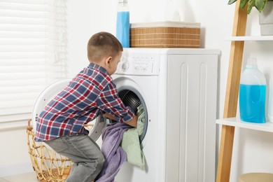 Little helper. Cute boy doing laundry at home