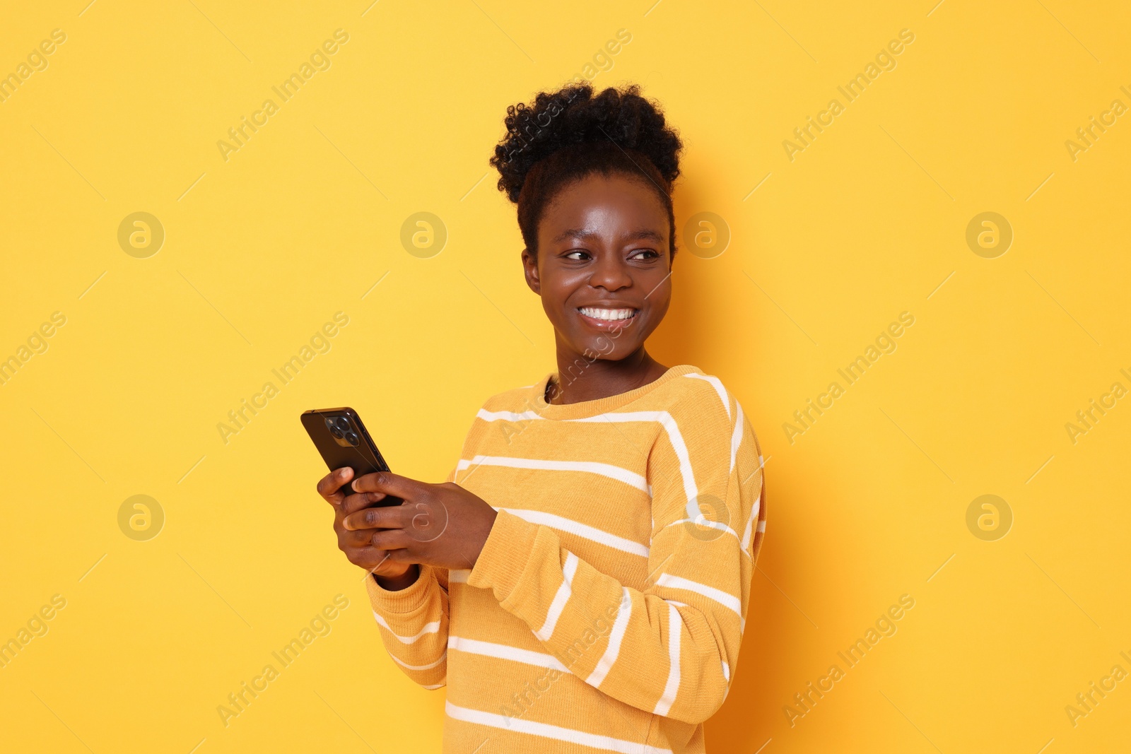 Photo of Happy woman with smartphone on yellow background