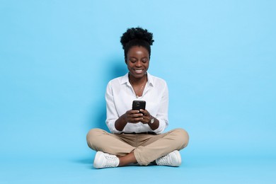 Photo of Happy woman with smartphone on light blue background