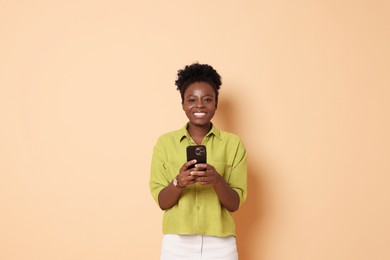 Happy woman with smartphone on beige background