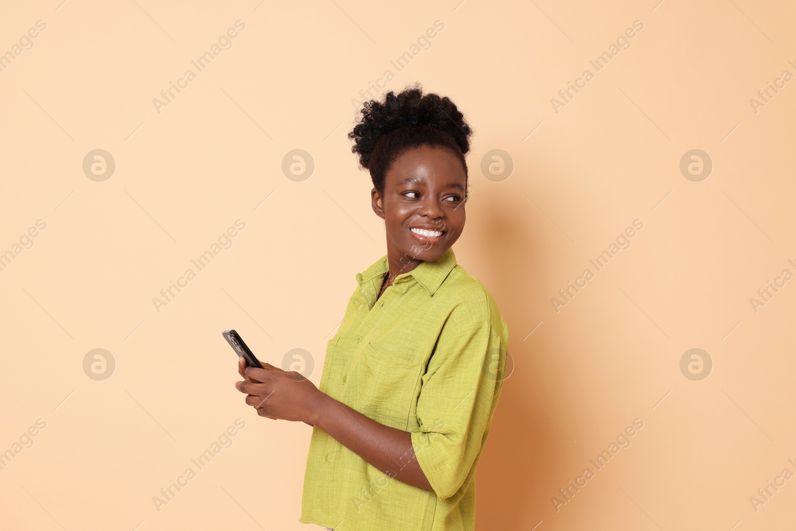 Photo of Happy woman with smartphone on beige background