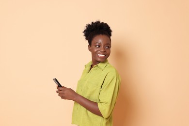 Happy woman with smartphone on beige background