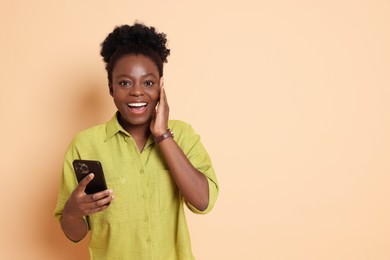 Happy woman with smartphone on beige background. Space for text