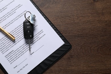 Photo of Car key and purchase agreement on wooden table, top view with space for text. Buying auto