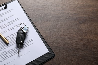 Photo of Car key and purchase agreement on wooden table, space for text. Buying auto