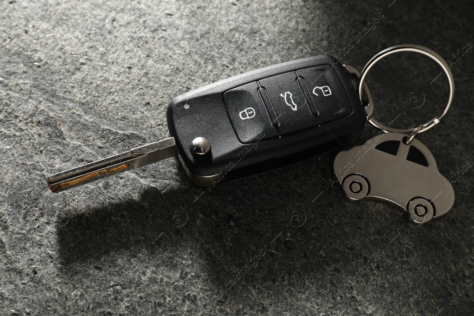 Photo of Car key with keychain on grey table, closeup. Buying auto