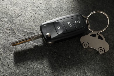 Car key with keychain on grey table, closeup. Buying auto