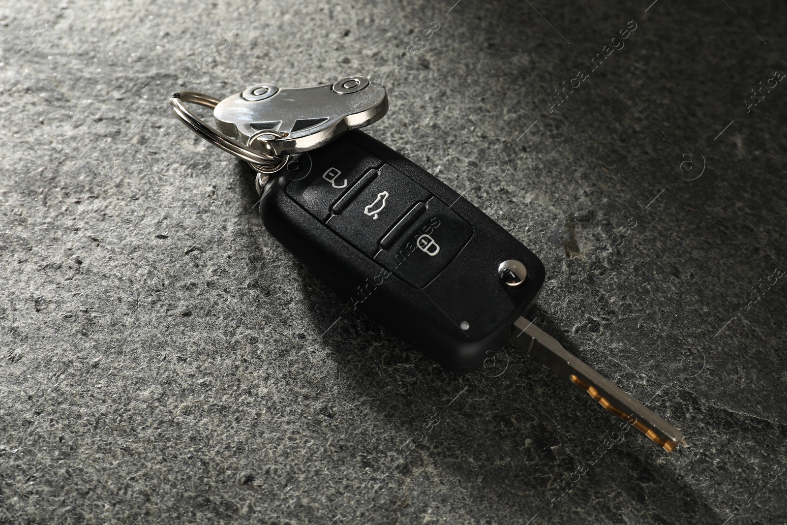 Photo of Car key with keychain on grey table, closeup. Buying auto