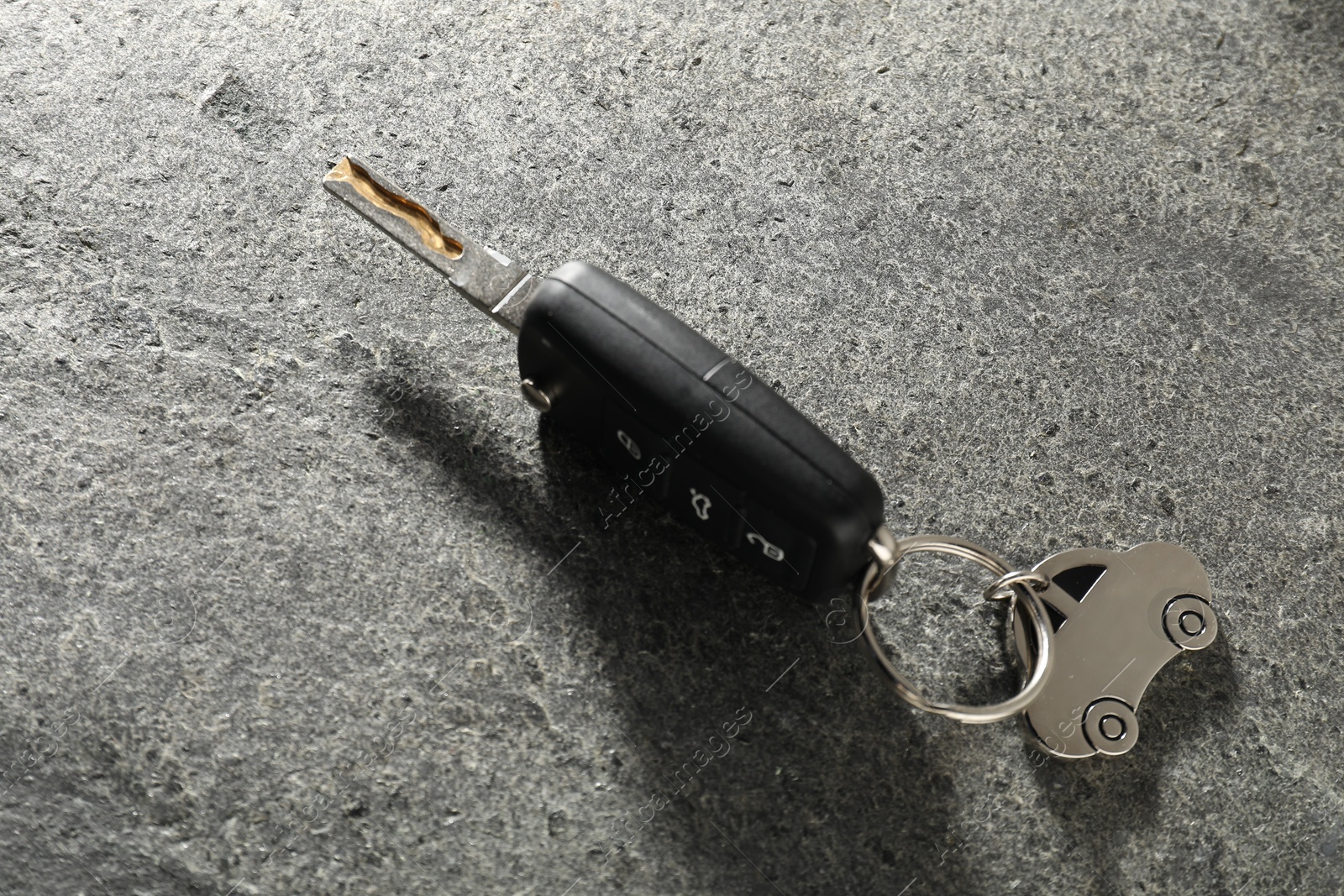 Photo of Car key with keychain on grey table, closeup. Buying auto