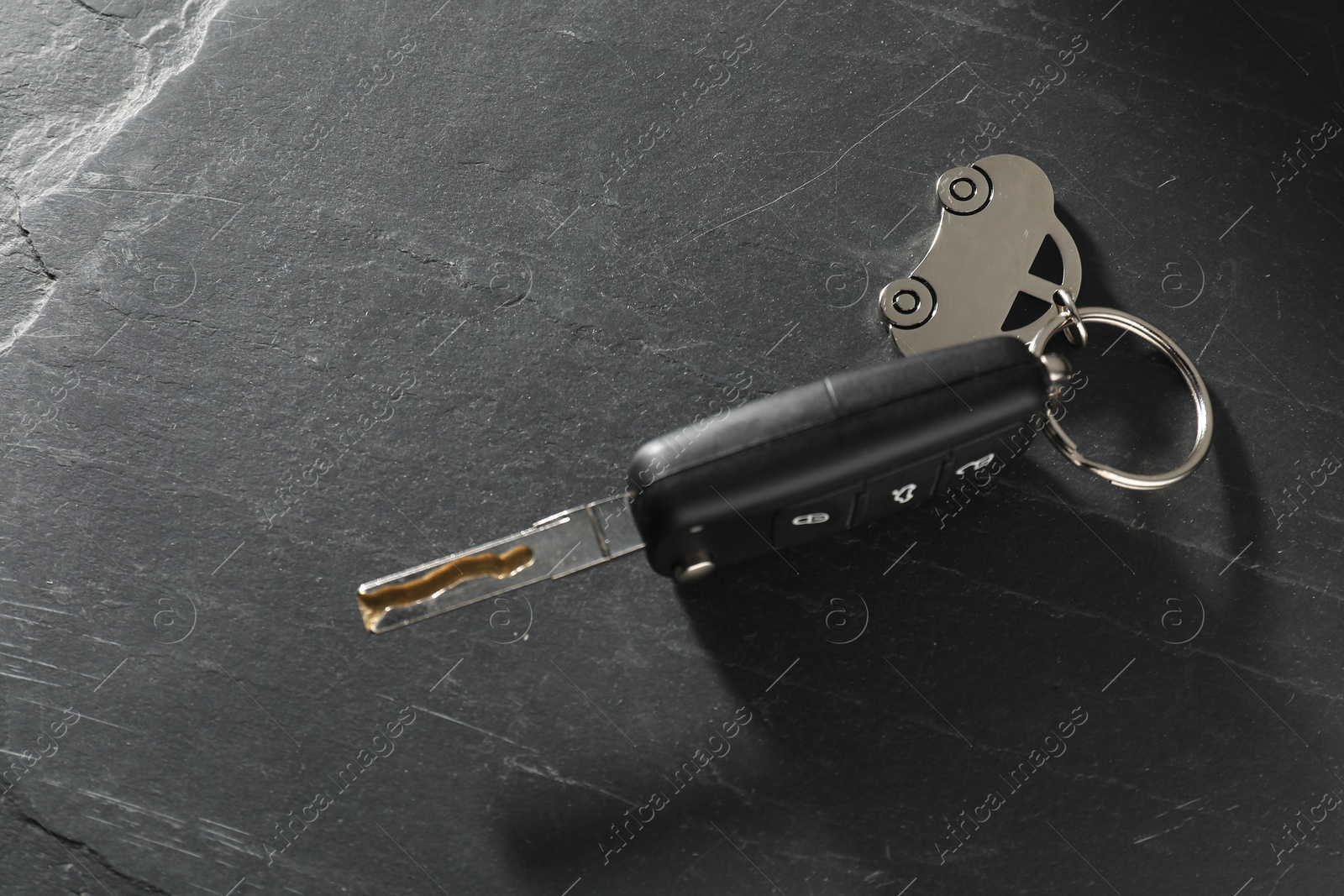 Photo of Car key with keychain on grey table, closeup. Buying auto