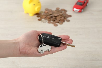 Photo of Woman with car key at light wooden table, closeup. Buying auto