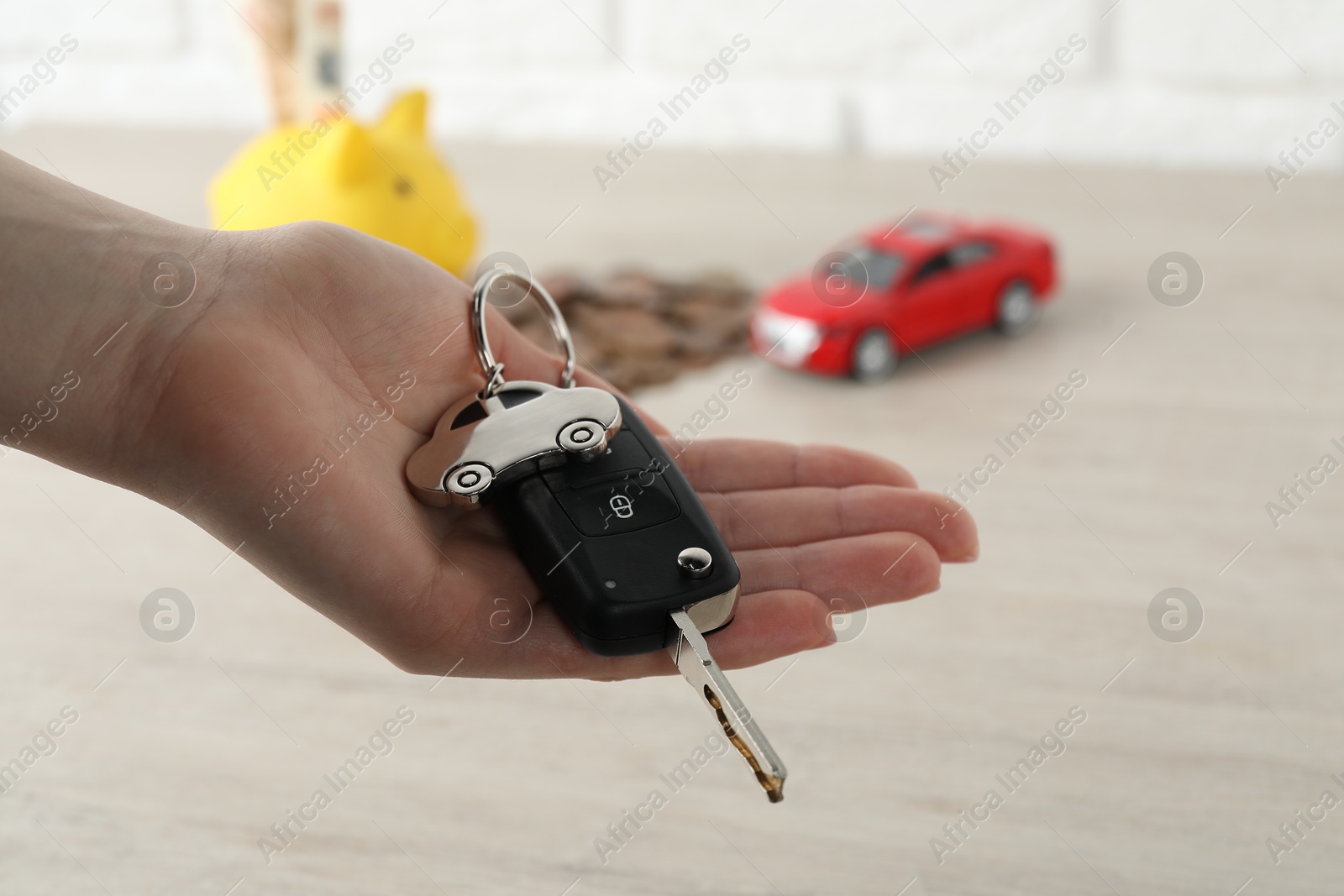 Photo of Woman with car key at light wooden table, closeup. Buying auto