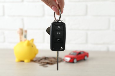 Photo of Woman with car key at light wooden table, closeup. Buying auto