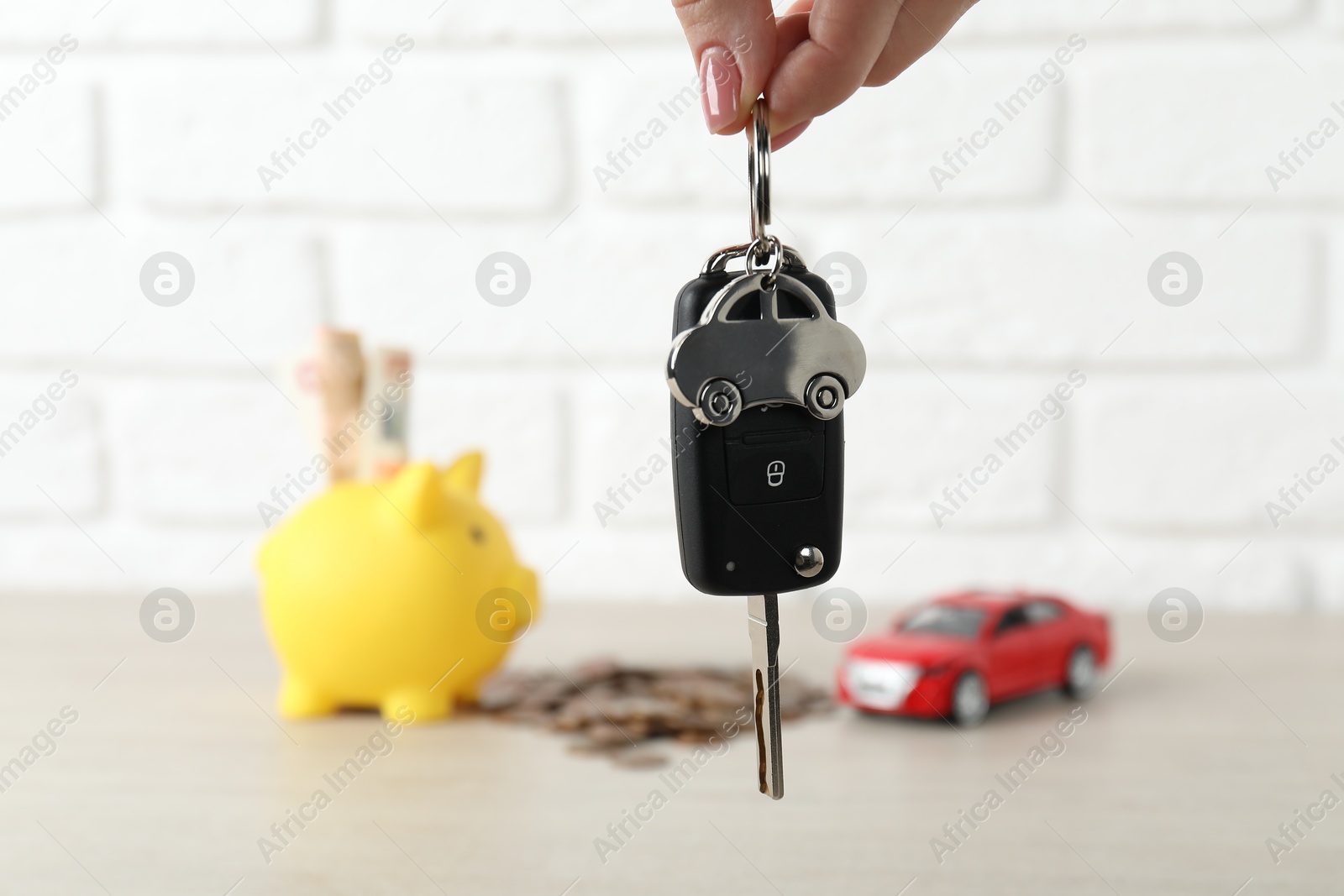 Photo of Woman with car key at light wooden table, closeup. Buying auto