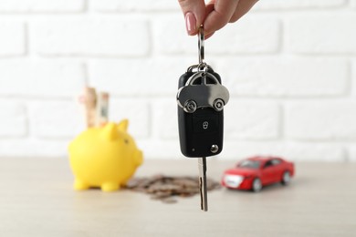 Photo of Woman with car key at light wooden table, closeup. Buying auto