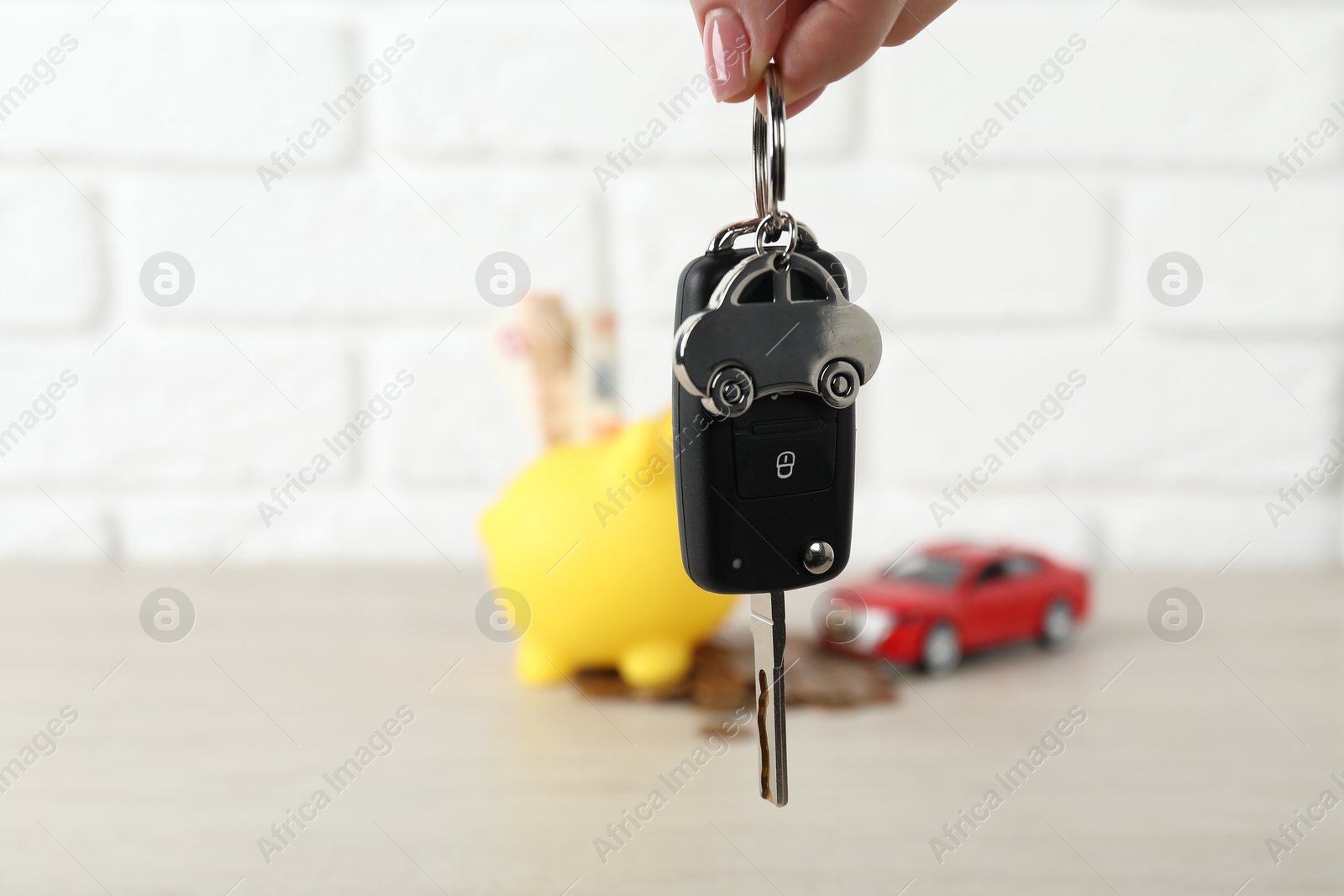 Photo of Woman with car key at light wooden table, closeup. Buying auto