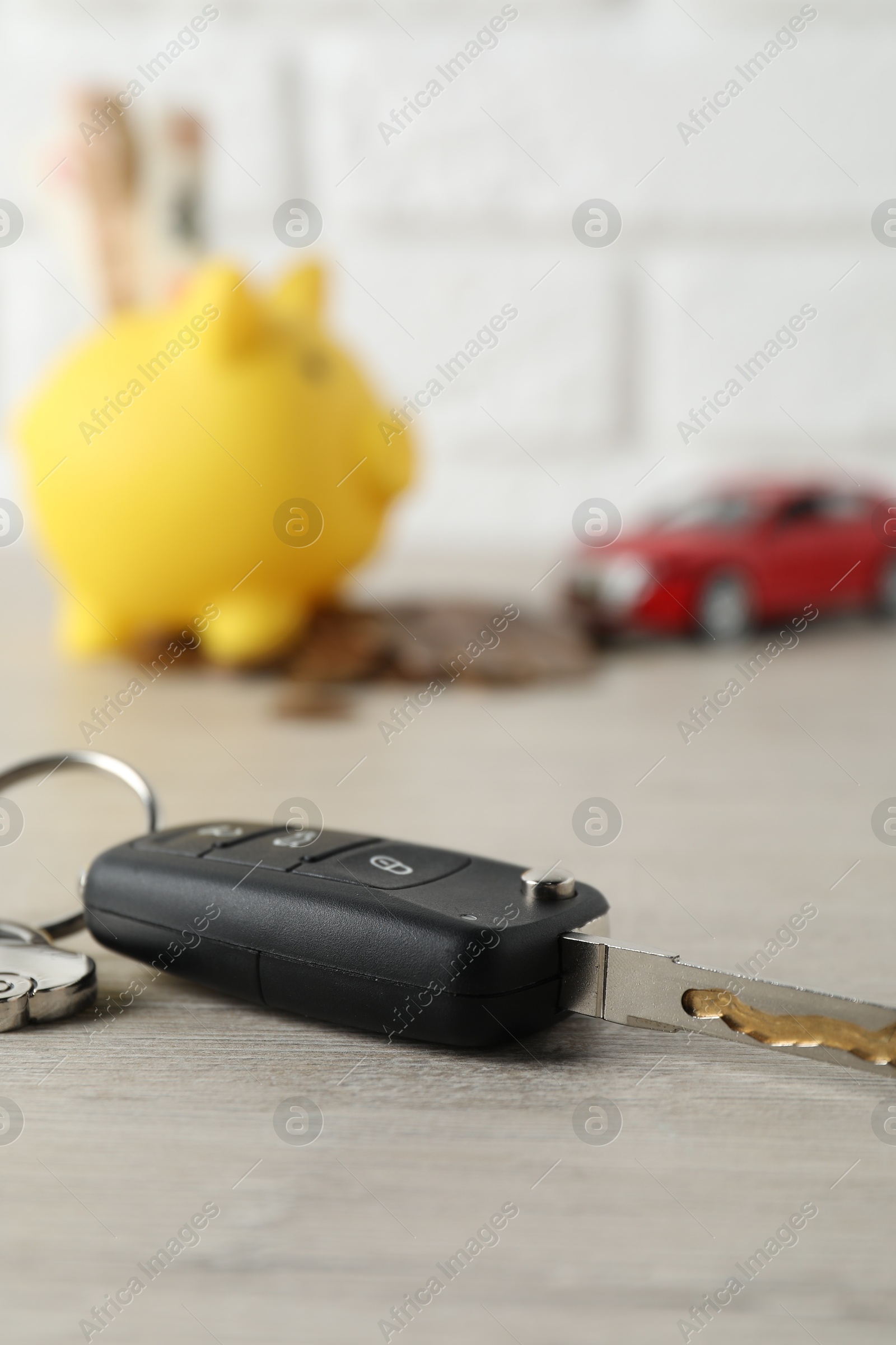 Photo of Car key with keychain on light wooden table, closeup. Buying auto