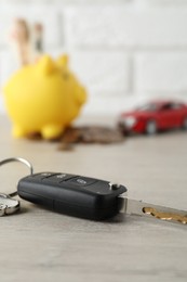 Photo of Car key with keychain on light wooden table, closeup. Buying auto