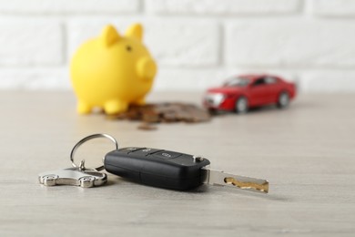 Photo of Car key with keychain on light wooden table, closeup. Buying auto