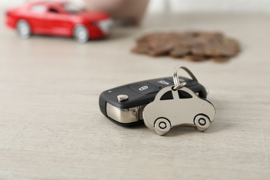 Photo of Car key with keychain on light wooden table, closeup. Buying auto