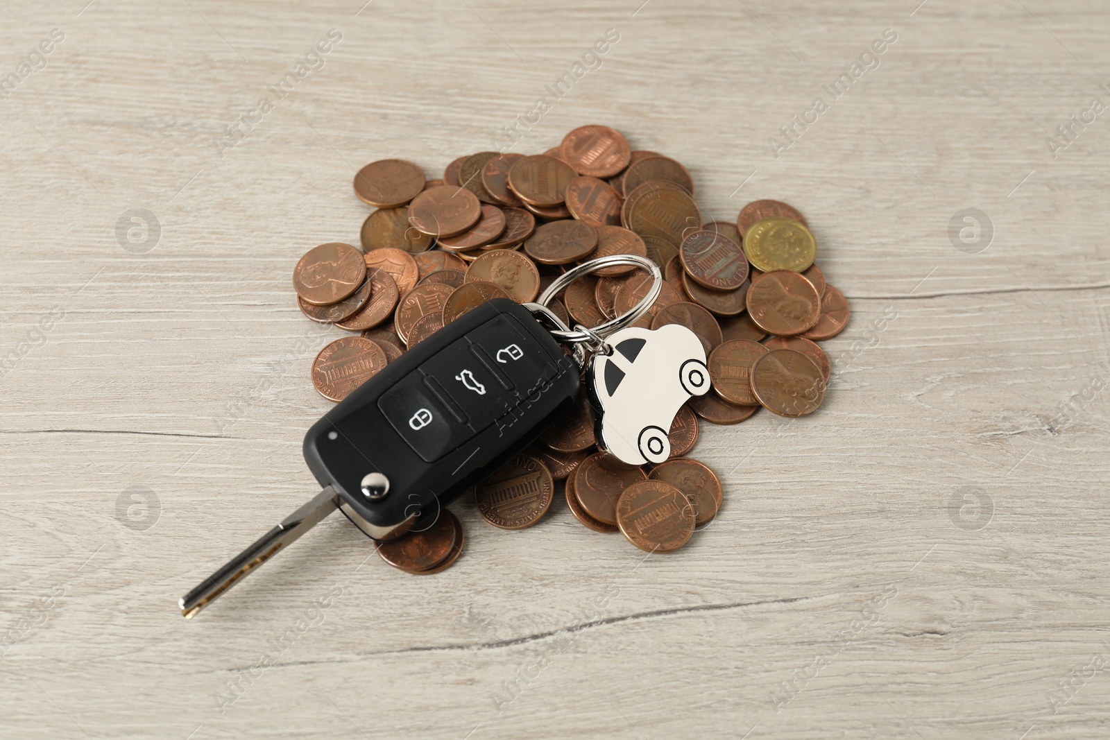 Photo of Car key and coins on light wooden table, closeup. Buying auto