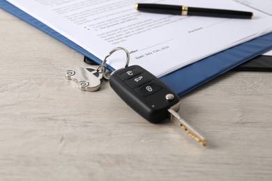 Photo of Car key and purchase agreement on wooden table, closeup. Buying auto