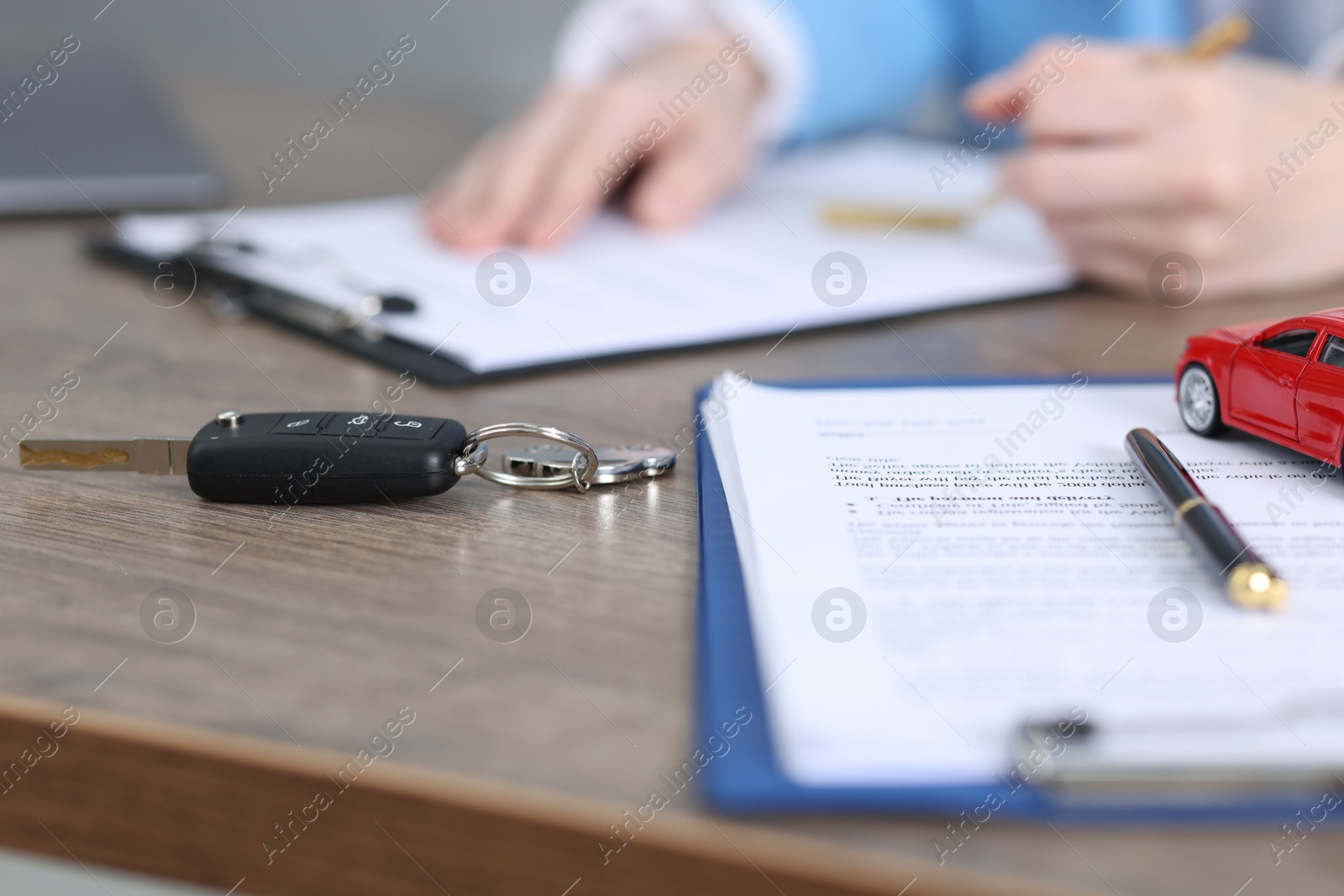 Photo of Car key, model and purchase agreement on wooden table, selective focus. Buying auto