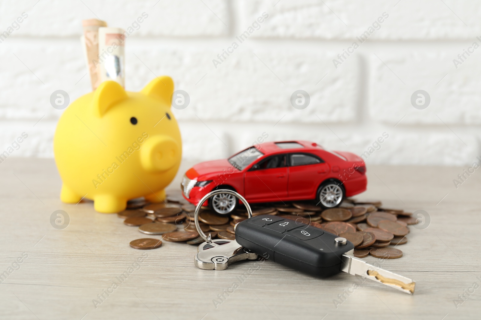 Photo of Car key, model, piggybank and coins on light background