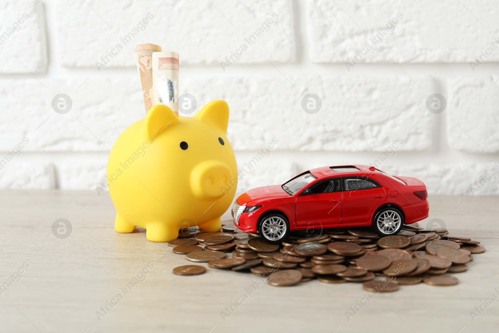 Photo of Car model, piggybank and coins on light background