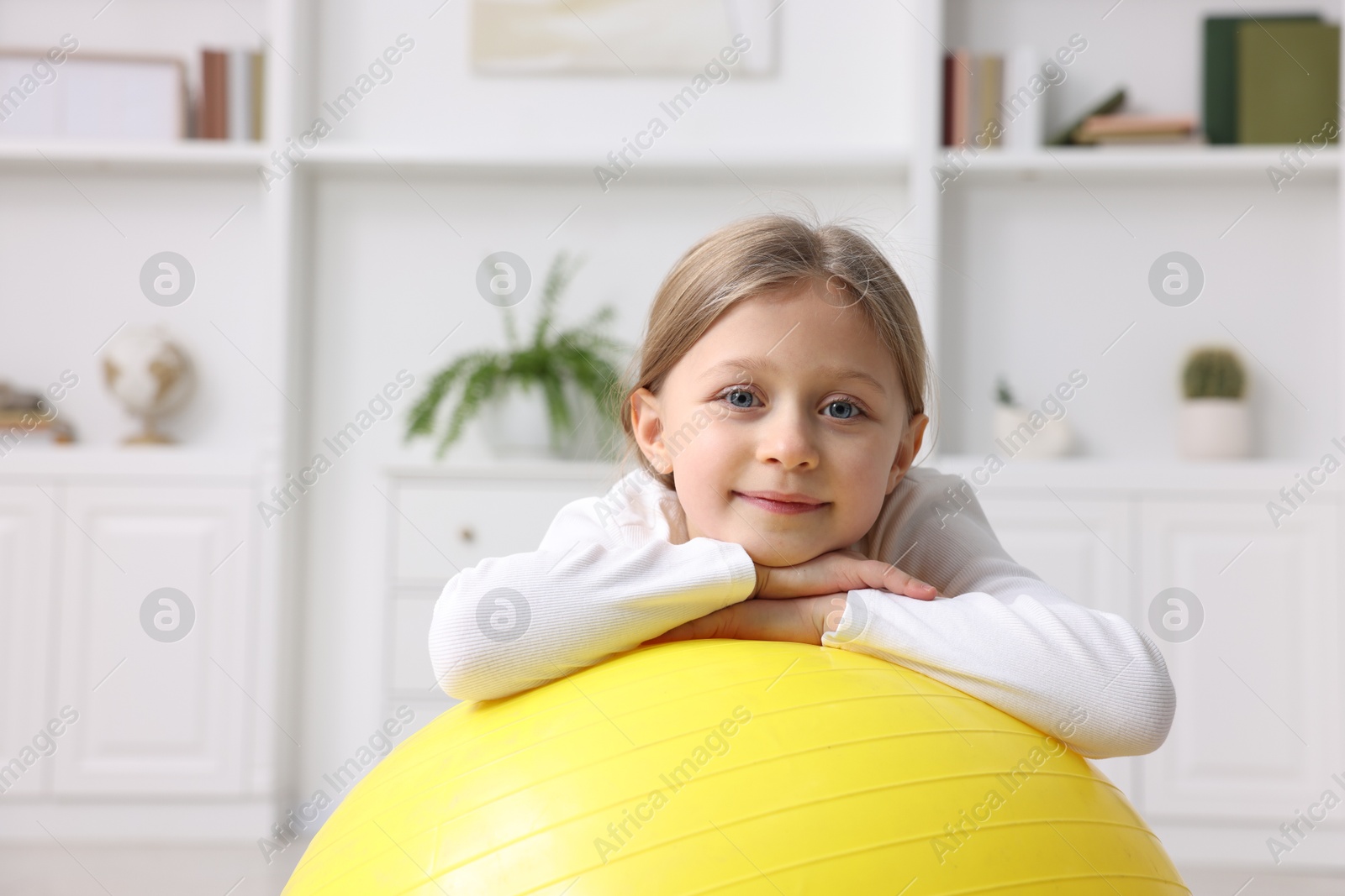 Photo of Cute little girl with fitness ball indoors