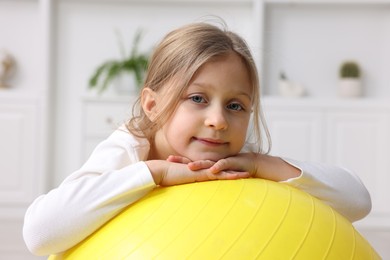 Photo of Cute little girl with fitness ball indoors