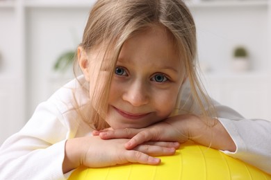 Cute little girl with fitness ball indoors