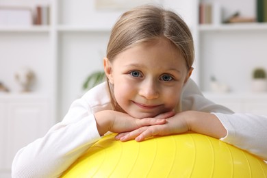 Cute little girl with fitness ball indoors