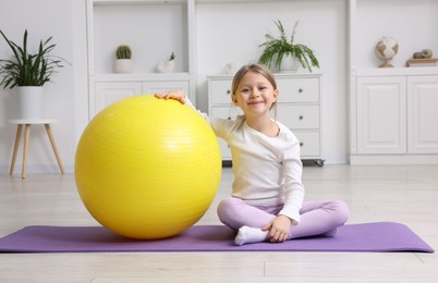 Photo of Cute little girl with fitness ball indoors