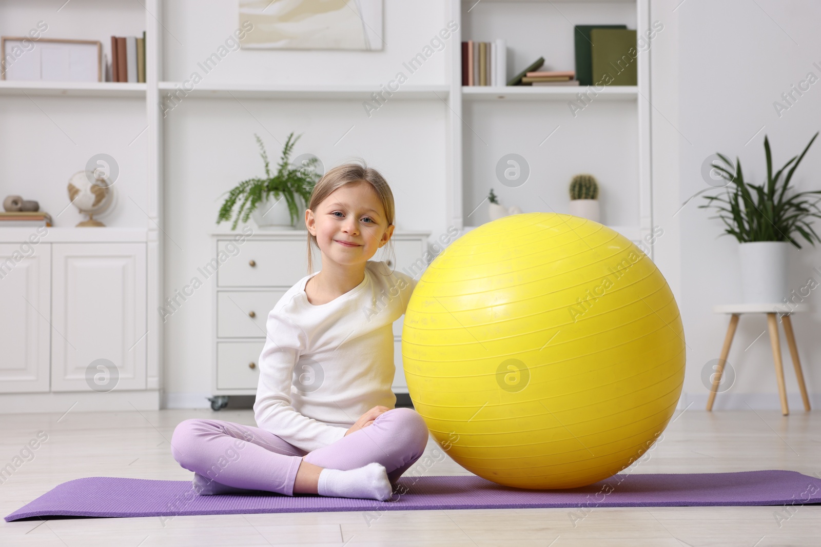 Photo of Cute little girl with fitness ball indoors