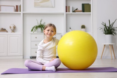 Photo of Cute little girl with fitness ball indoors