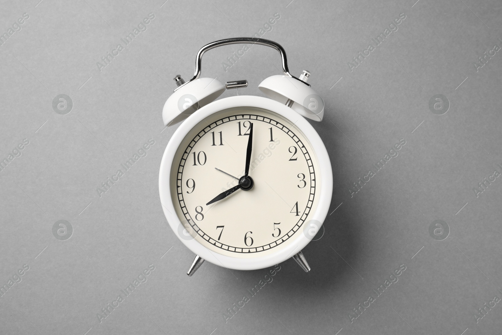 Photo of One white alarm clock on light grey background, top view