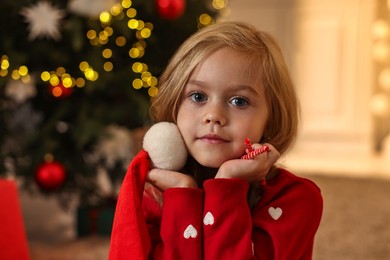 Photo of Little girl with Santa hat and candy canes at home. Christmas celebration