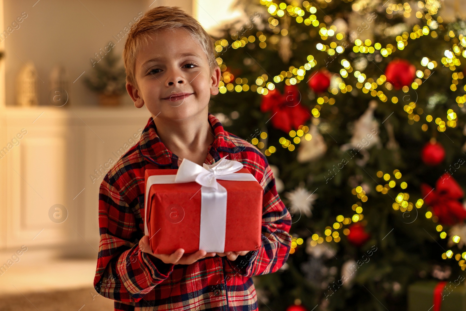 Photo of Little boy with Christmas box at home, space for text